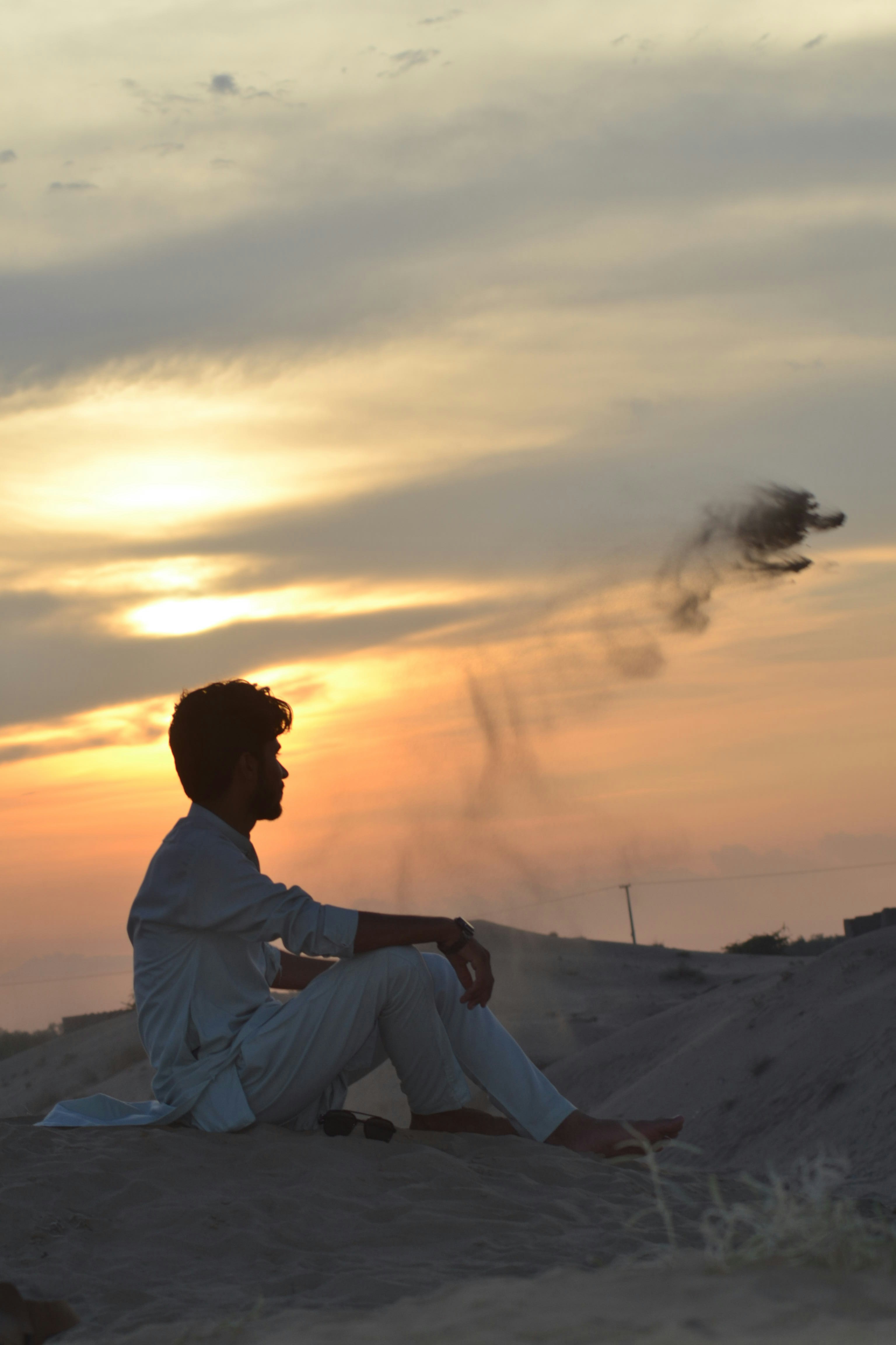 A man sitting on top of a sandy hill