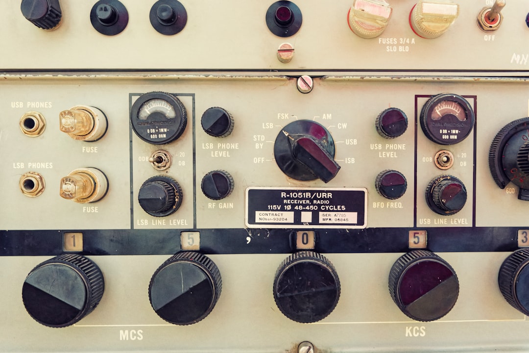 A bunch of knobs and switches on a wall, Radio control panel with various dials and knobs in a vintage design displayed in a studio setting - A detailed view of an antique radio control panel featuring multiple dials, knobs, and settings for audio adjustments.