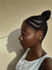 A woman with a white tank top and braids on her hair