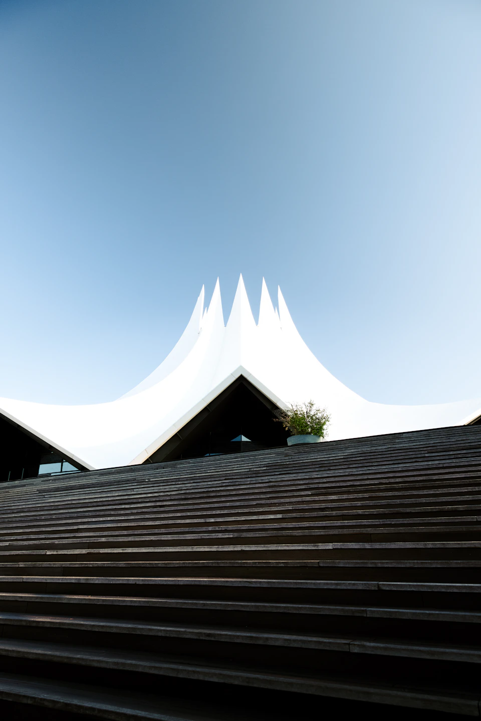 Large white tent with multiple spires stands tall against a clear blue sky
