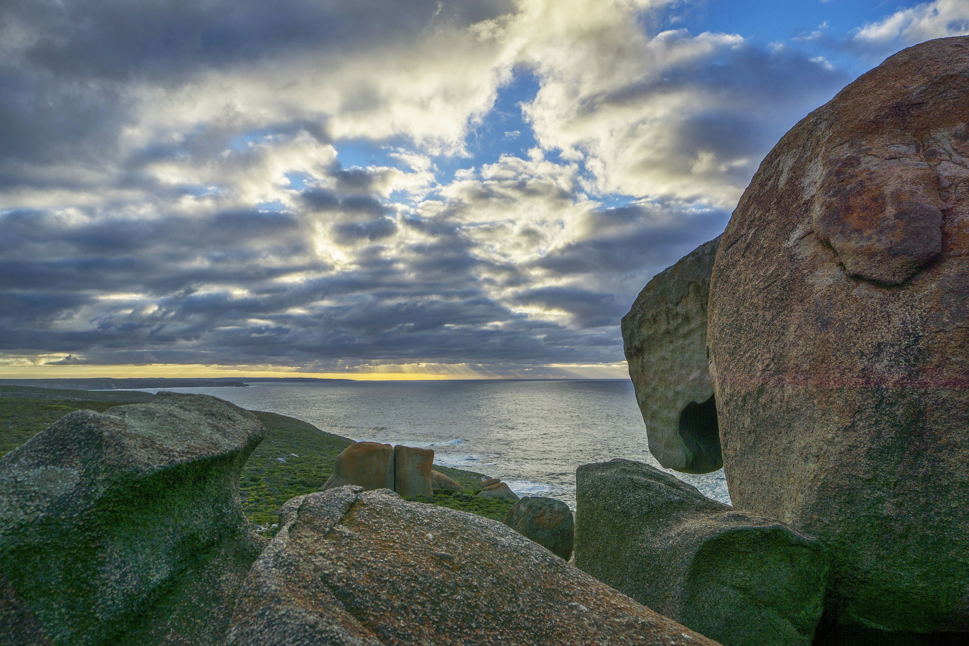 A large rock sitting on top of a lush green field, Remarkalbe rocks