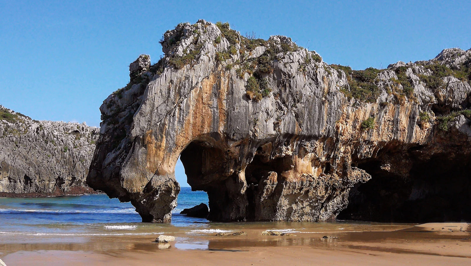 Arco de roca y arenal en la costa del norte de España