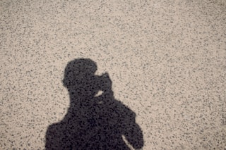 A shadow of a person holding a cell phone