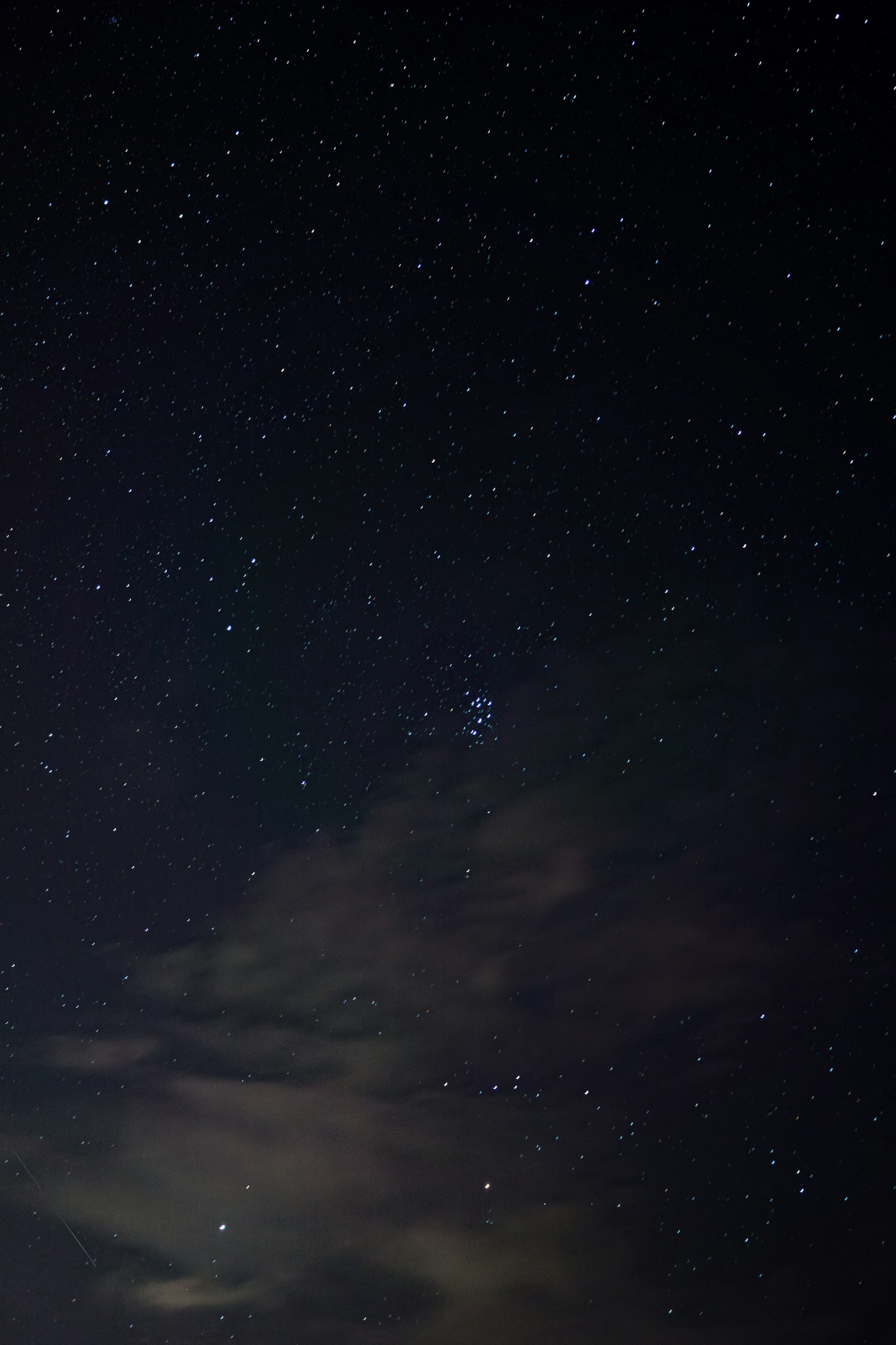 The night sky is filled with stars and clouds