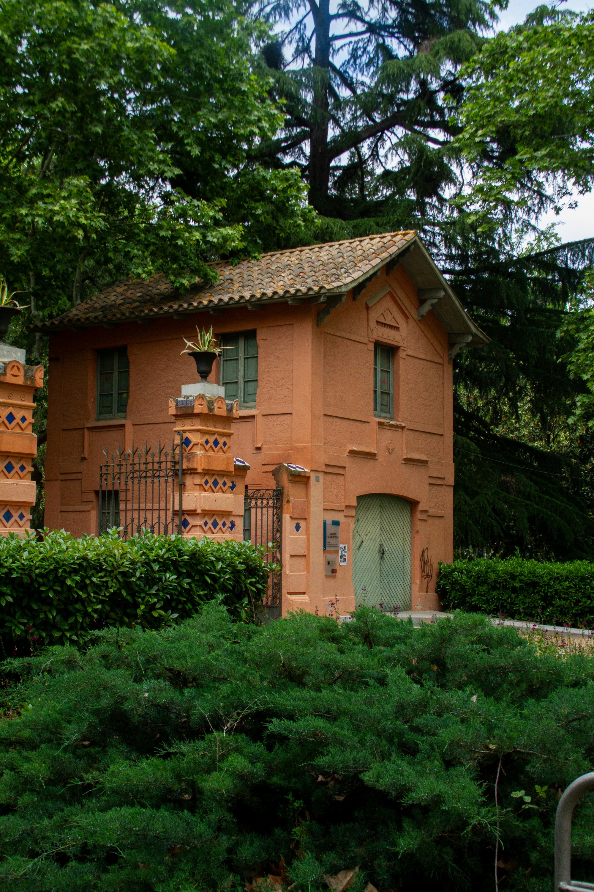 An orange house with a green door surrounded by trees
