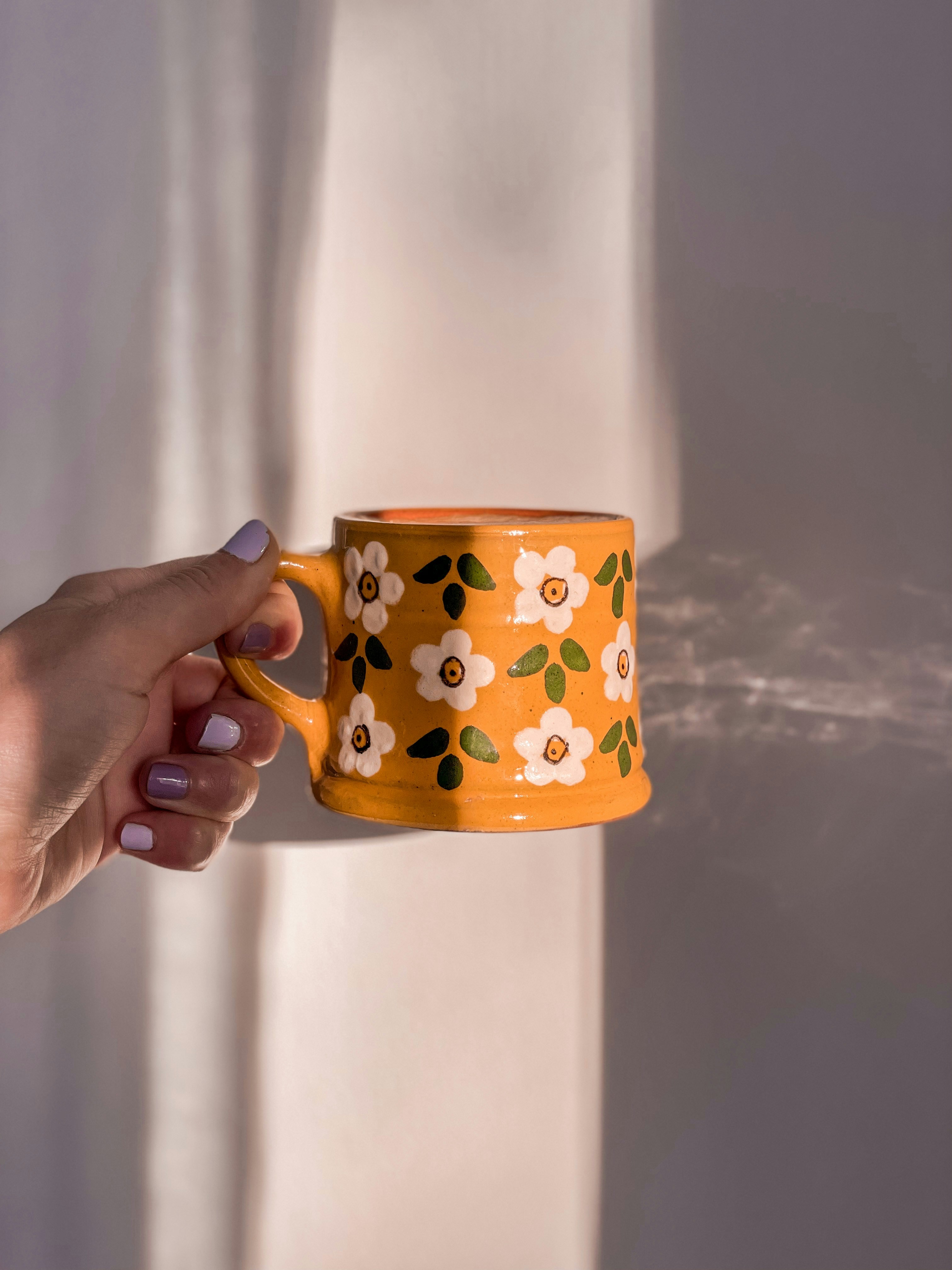 A person is holding a coffee cup with a spray of water coming out of it
