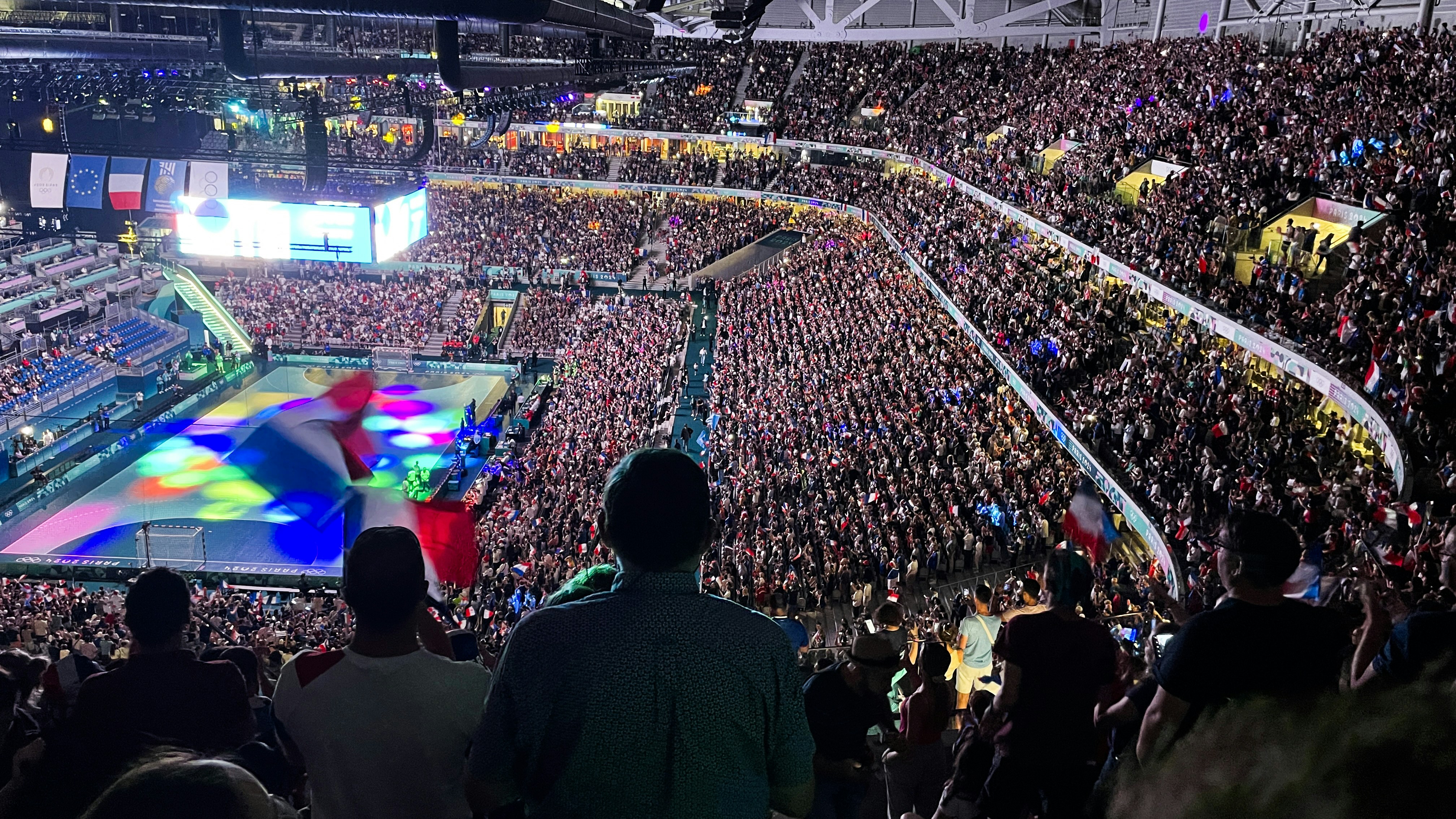 A crowd of people watching a game on a large screen