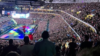 A crowd of people watching a game on a large screen
