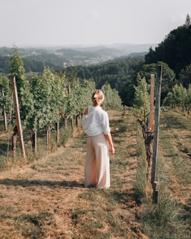 A woman standing in a field with trees in the background