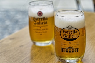 Two glasses of beer sitting on top of a wooden table