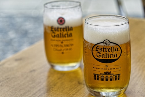 Two glasses of beer sitting on top of a wooden table