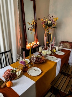 A dining room table set with plates and candles