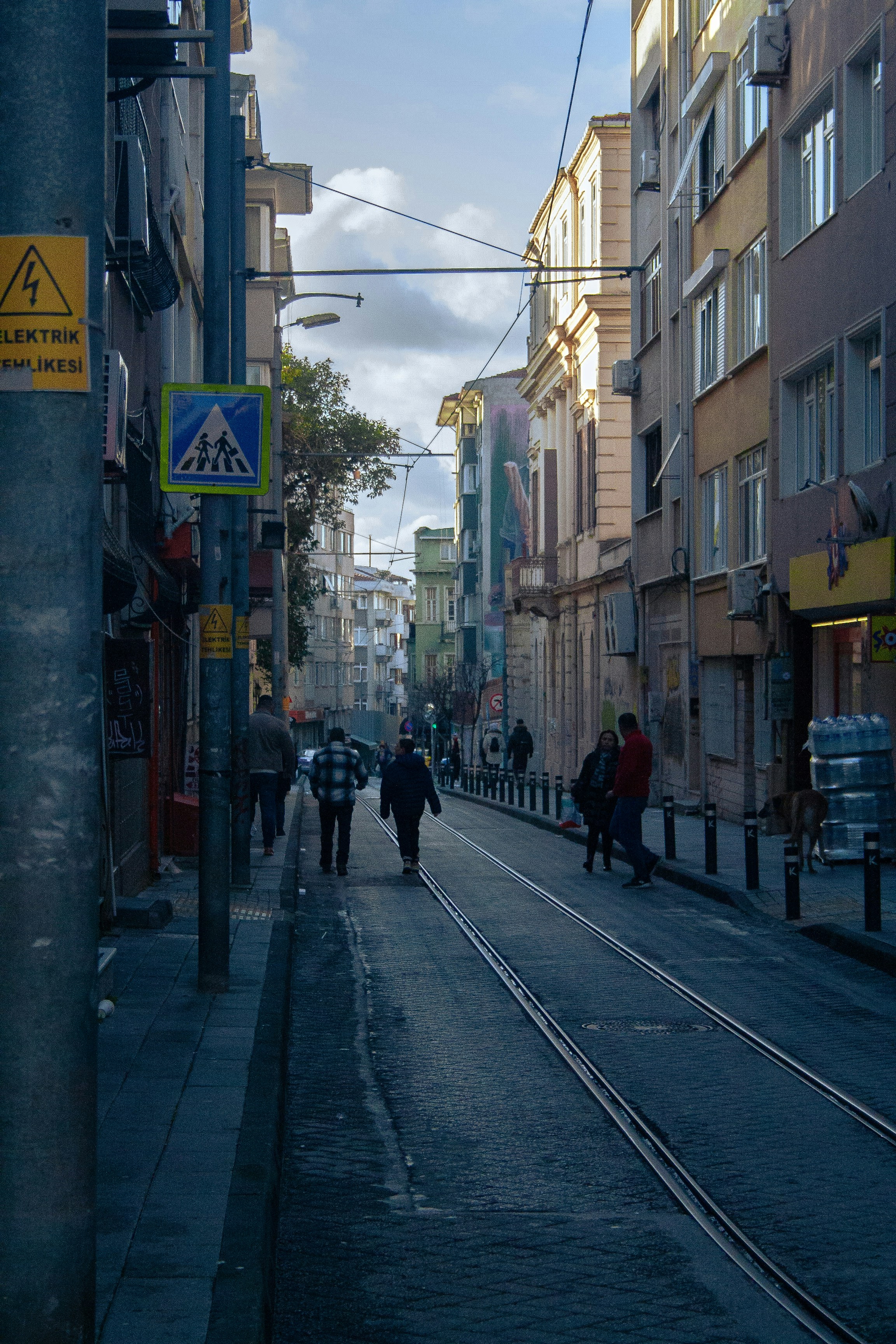 A group of people walking down a street next to tall buildings