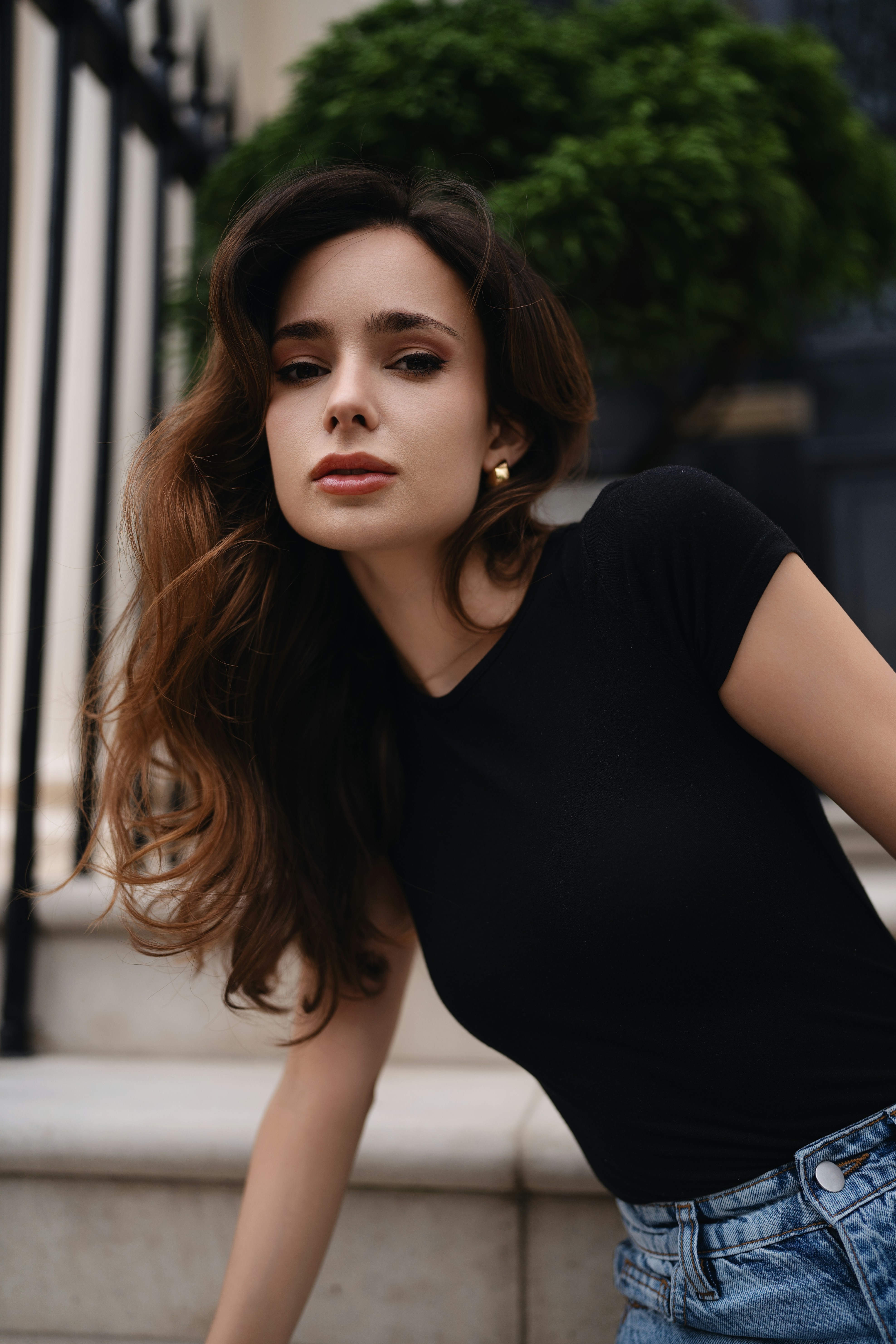 A woman leaning against a fence with her hand on her hip