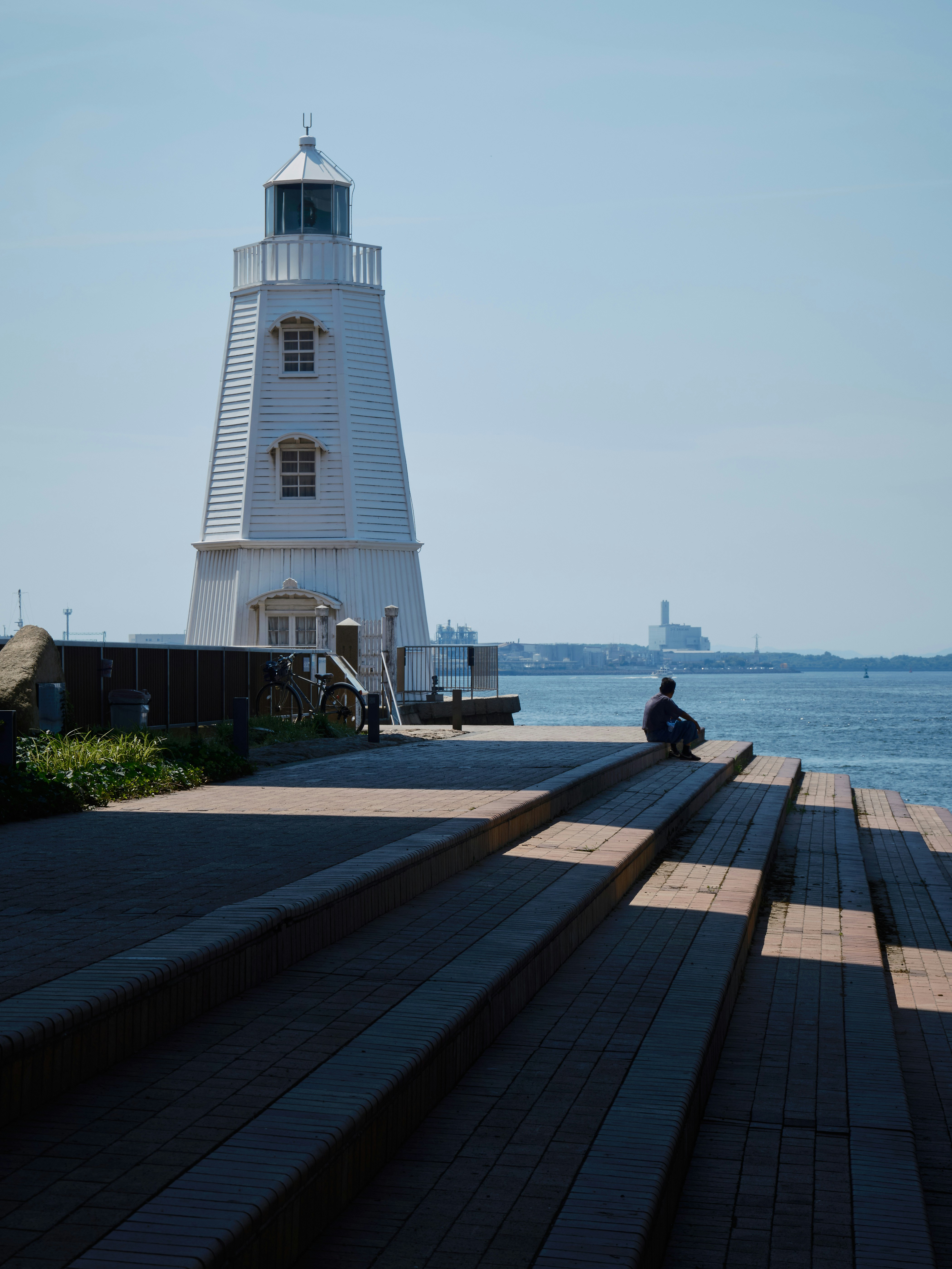 A person sitting on a bench near a lighthouse
