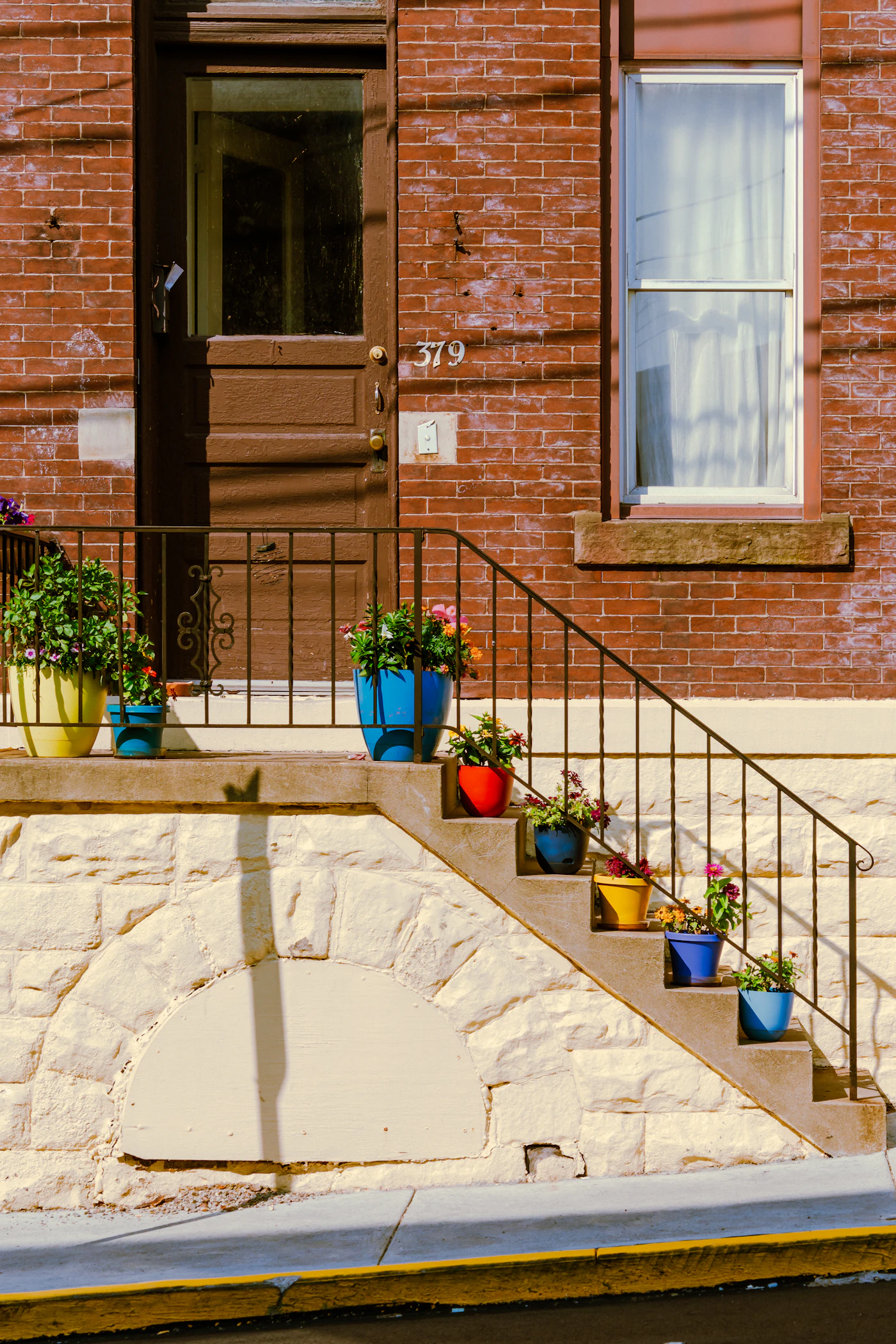 Brick front steps lined with potted flowers leading up to a doorway