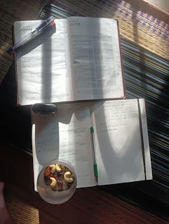 An open book sitting on top of a table next to a bowl of food