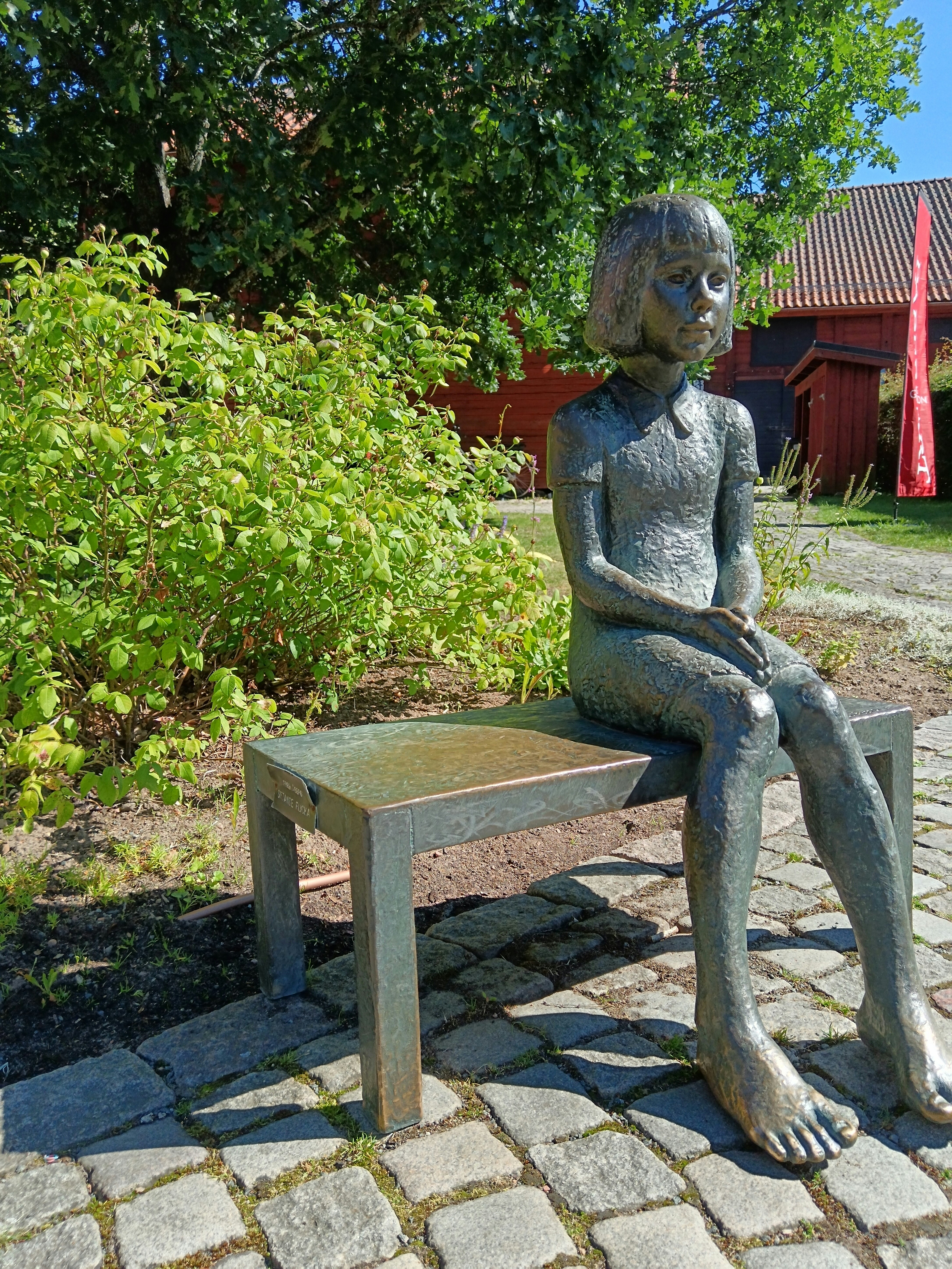 Eine Statue einer Person, die auf einer Bank sitzt