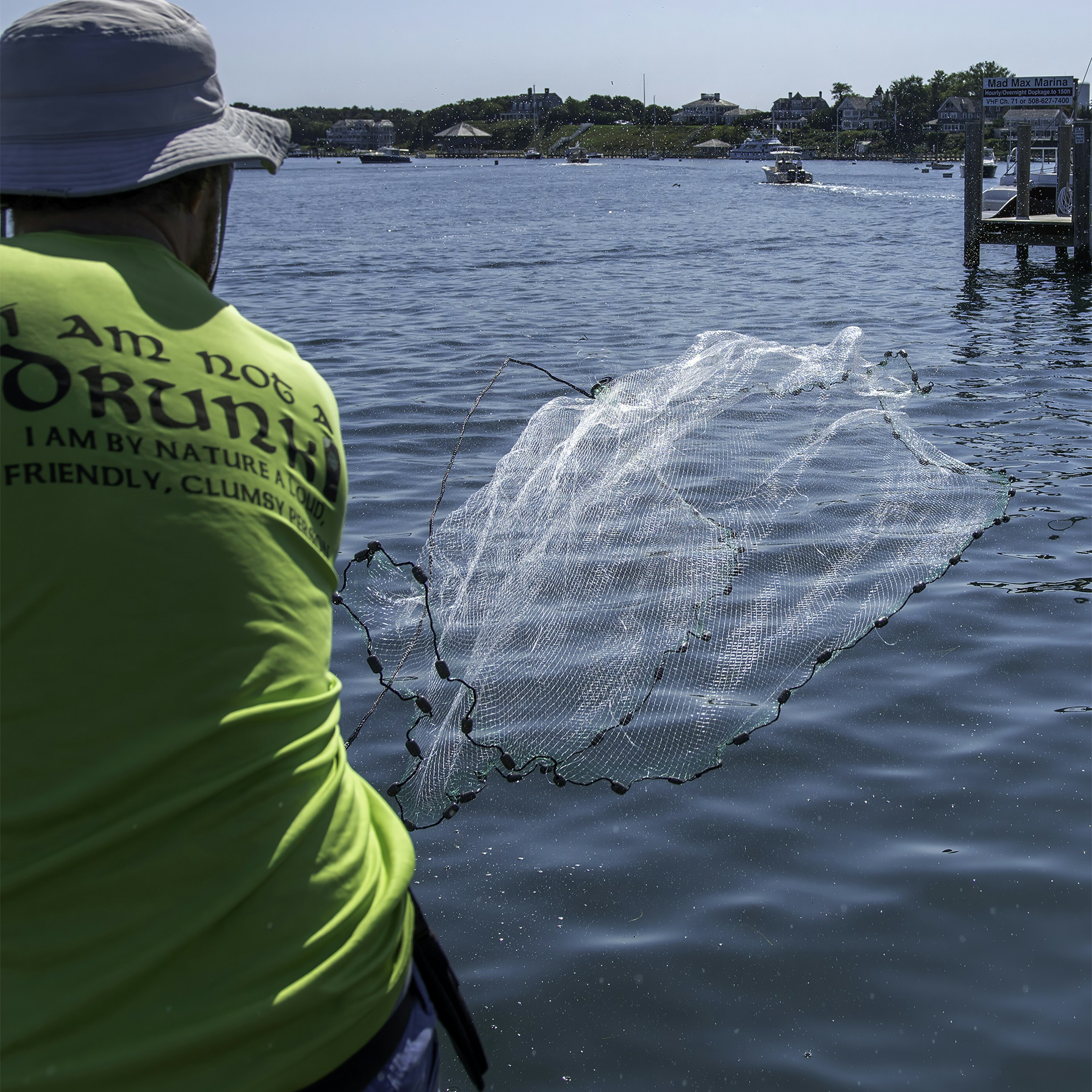 A man in a green shirt is throwing a net into the water