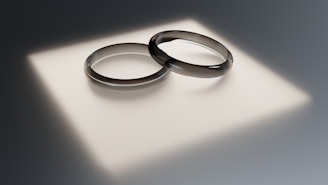 Two wedding rings sitting on top of a white surface