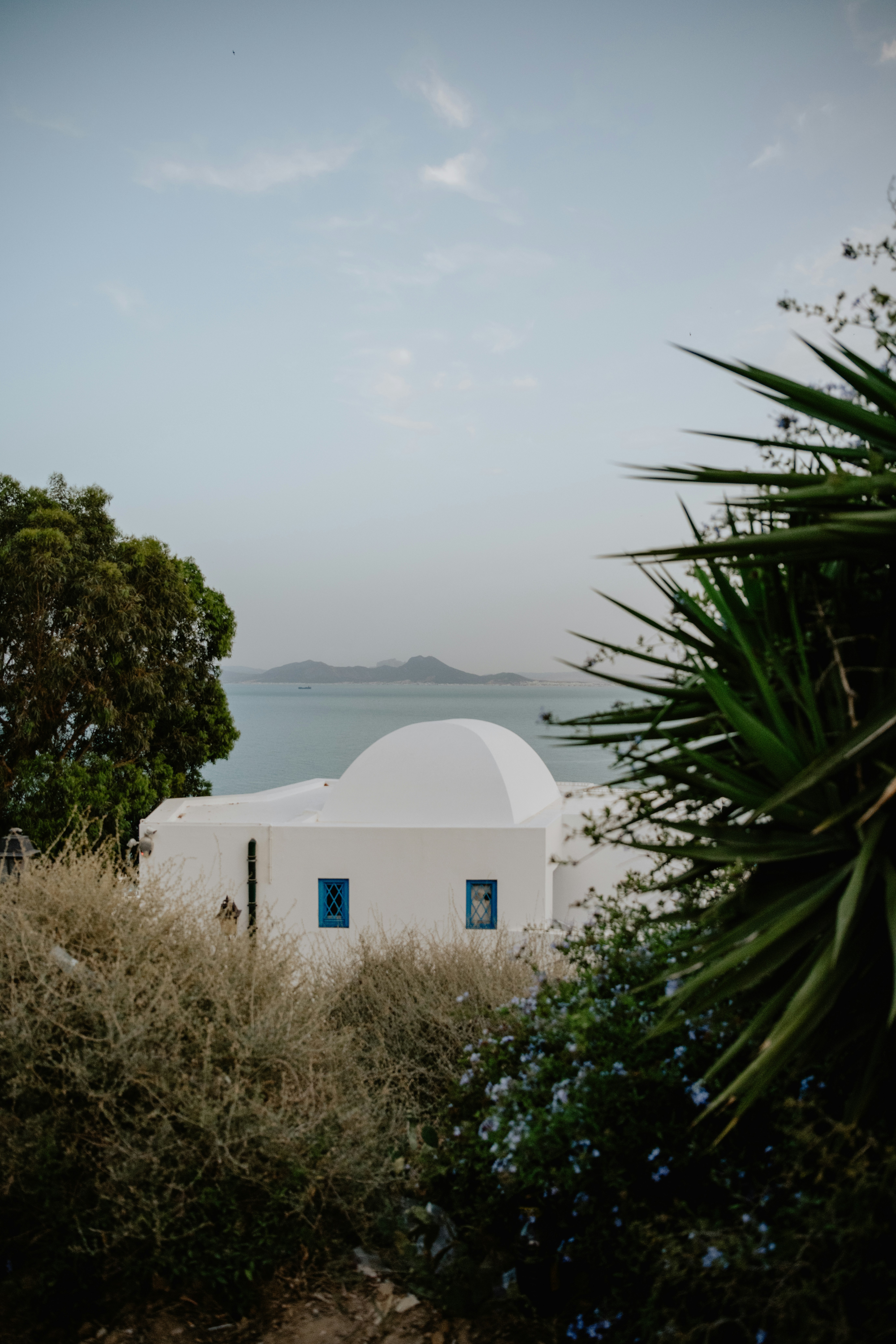 Um edifício branco com uma porta azul sentado no topo de uma colina