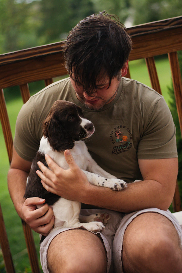 A man sitting on a bench holding a puppy