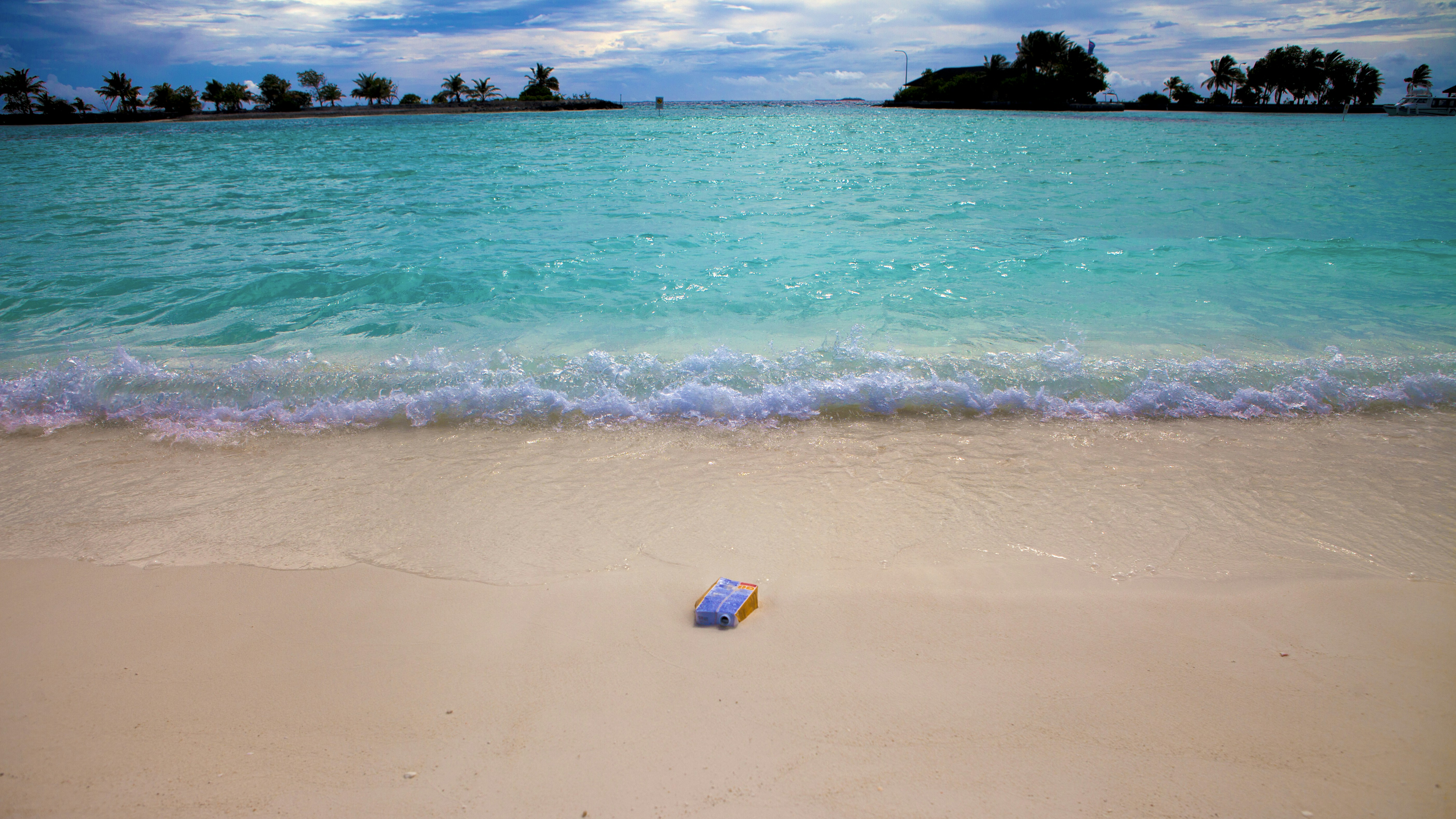 A blue bottle sitting on top of a sandy beach