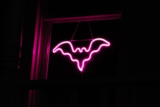 A neon sign with a bat hanging from it's side