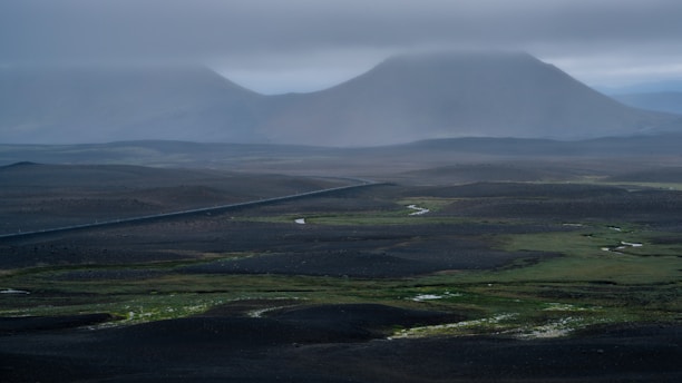 An aerial view of a mountain range with clouds in the sky