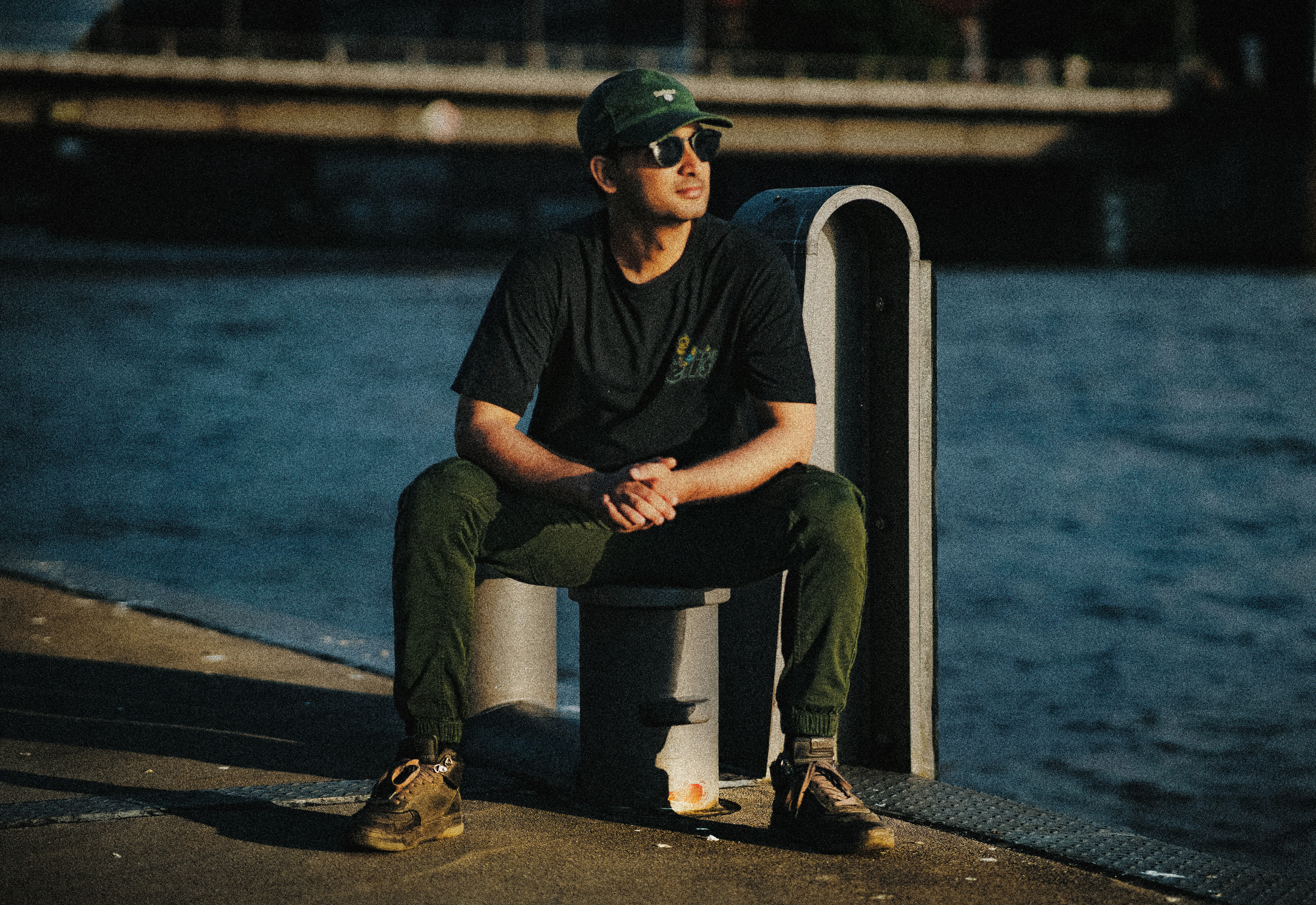 A man sitting on a post next to a body of water