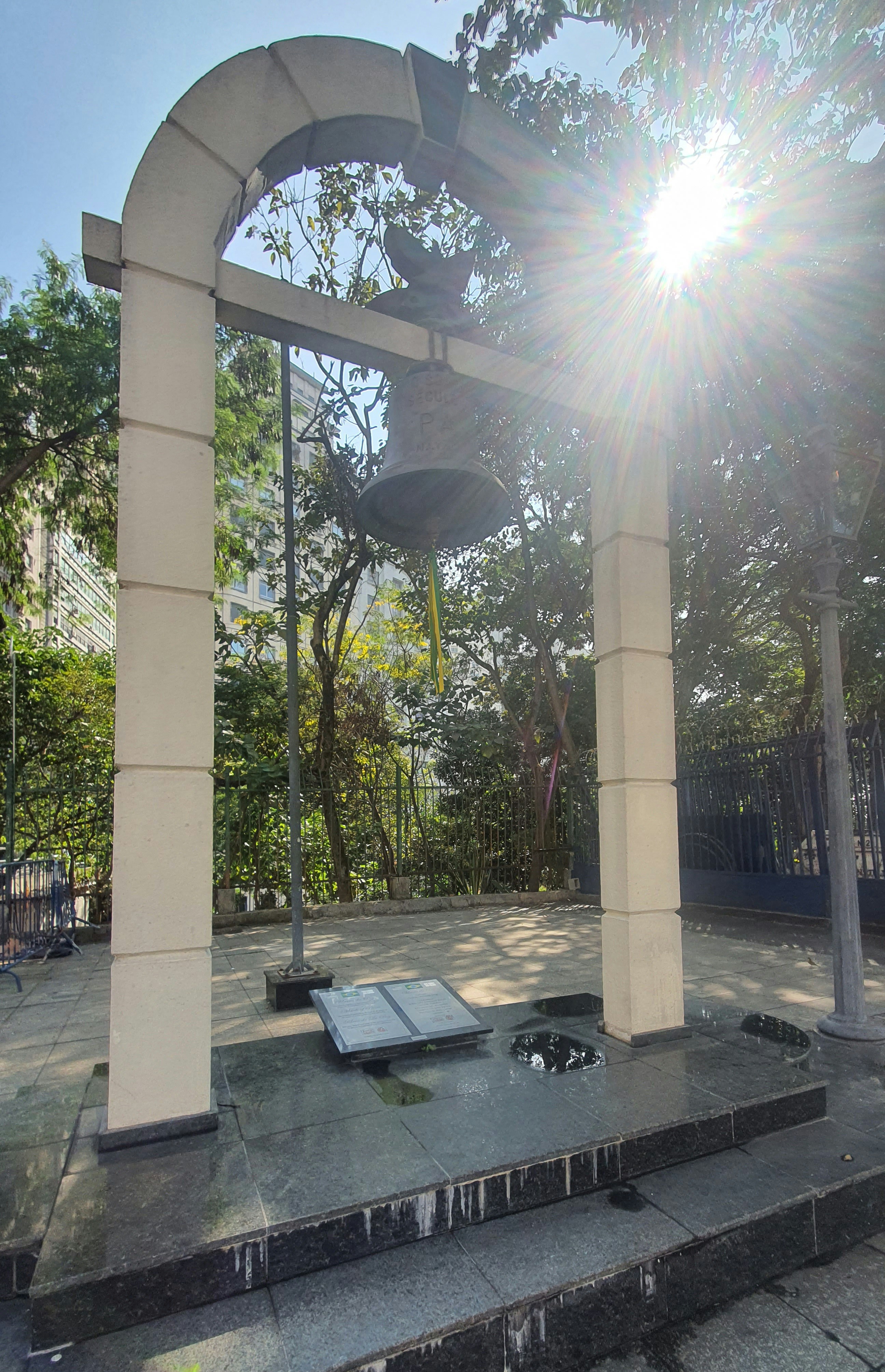 The sun shines brightly through the trees in a park