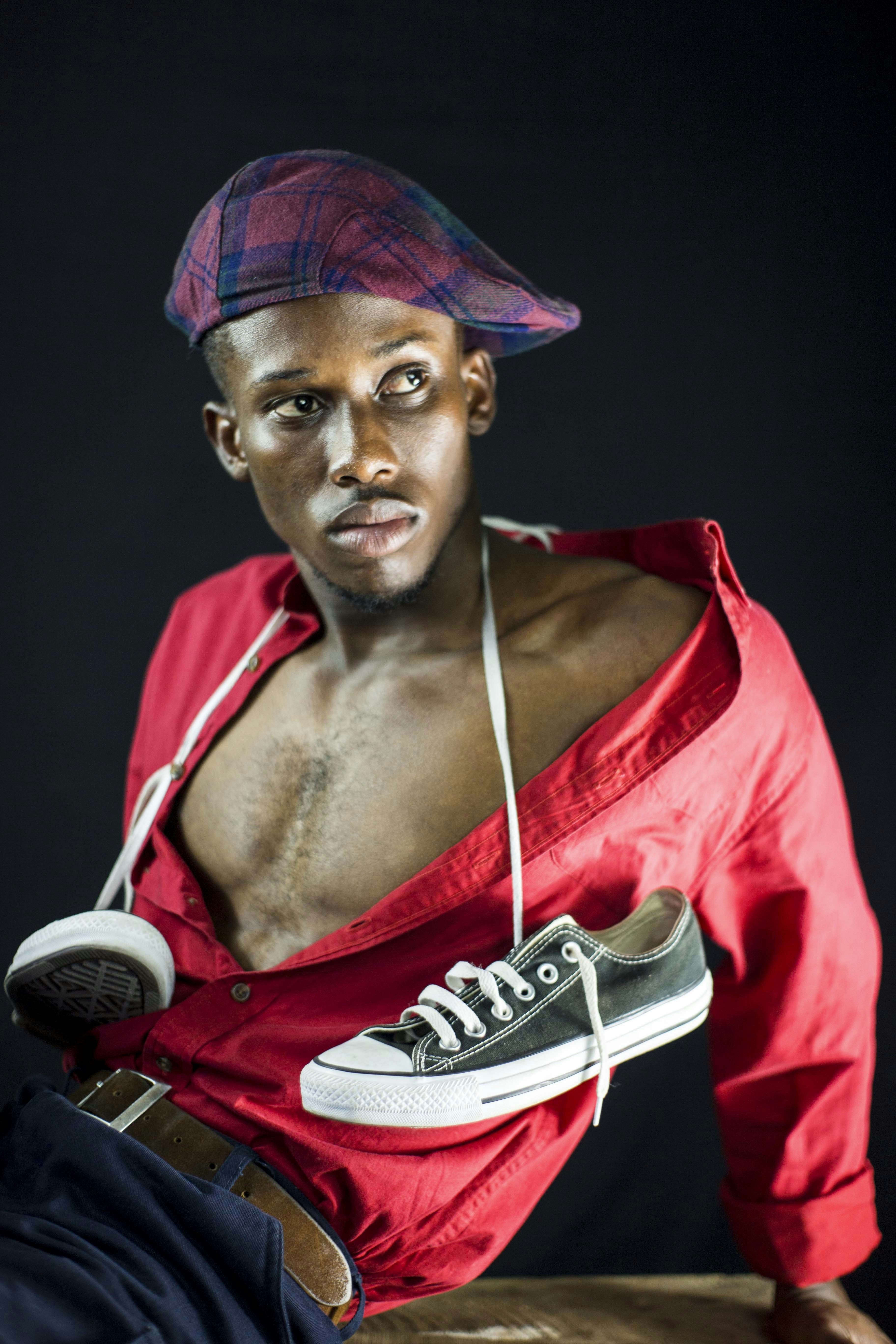 Um homem em uma camisa vermelha e chapéu sentado em um banquinho