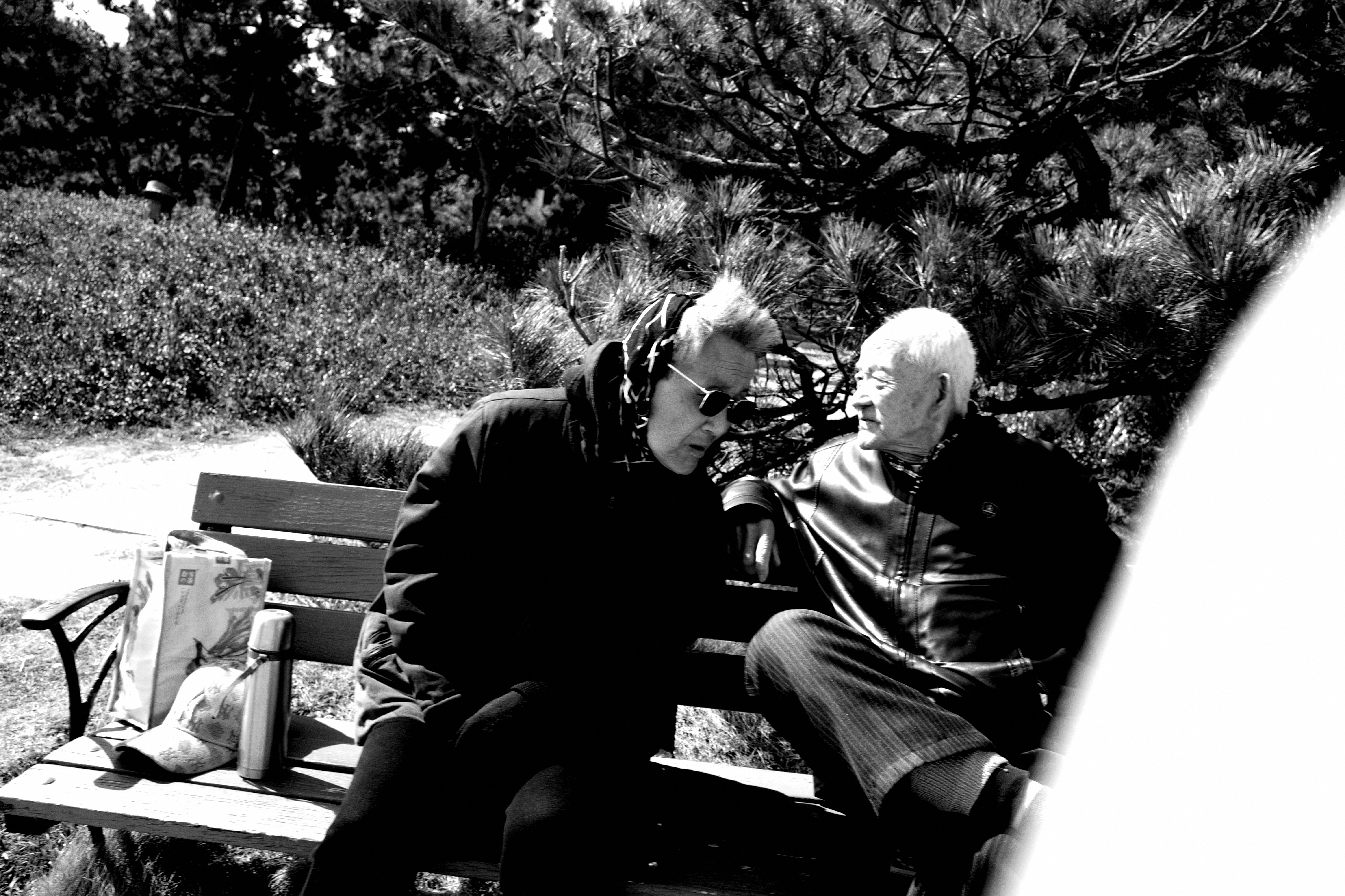 A couple of men sitting on top of a wooden bench