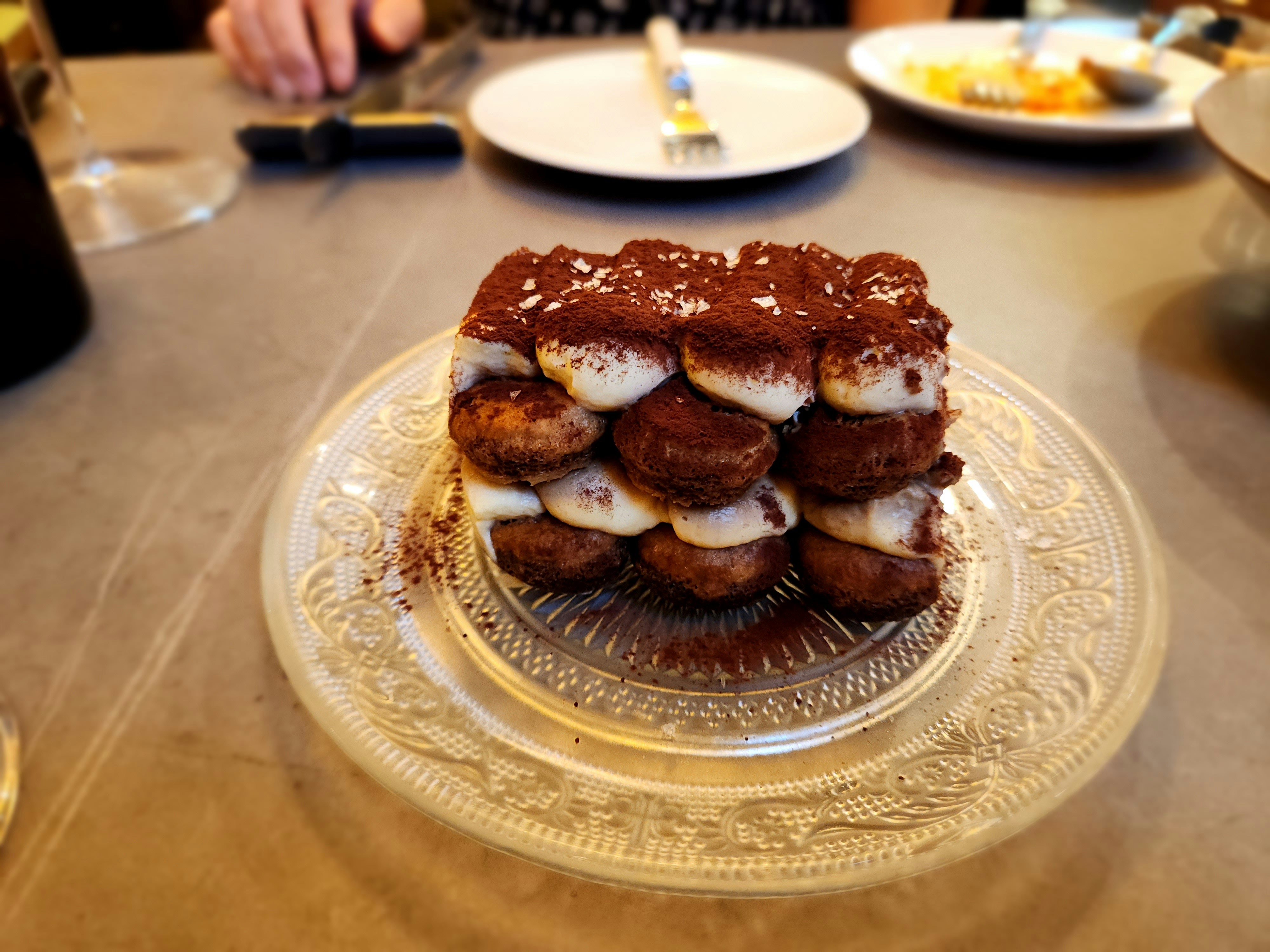 Layered tiramisu dessert dusted with cocoa powder in a glass dish