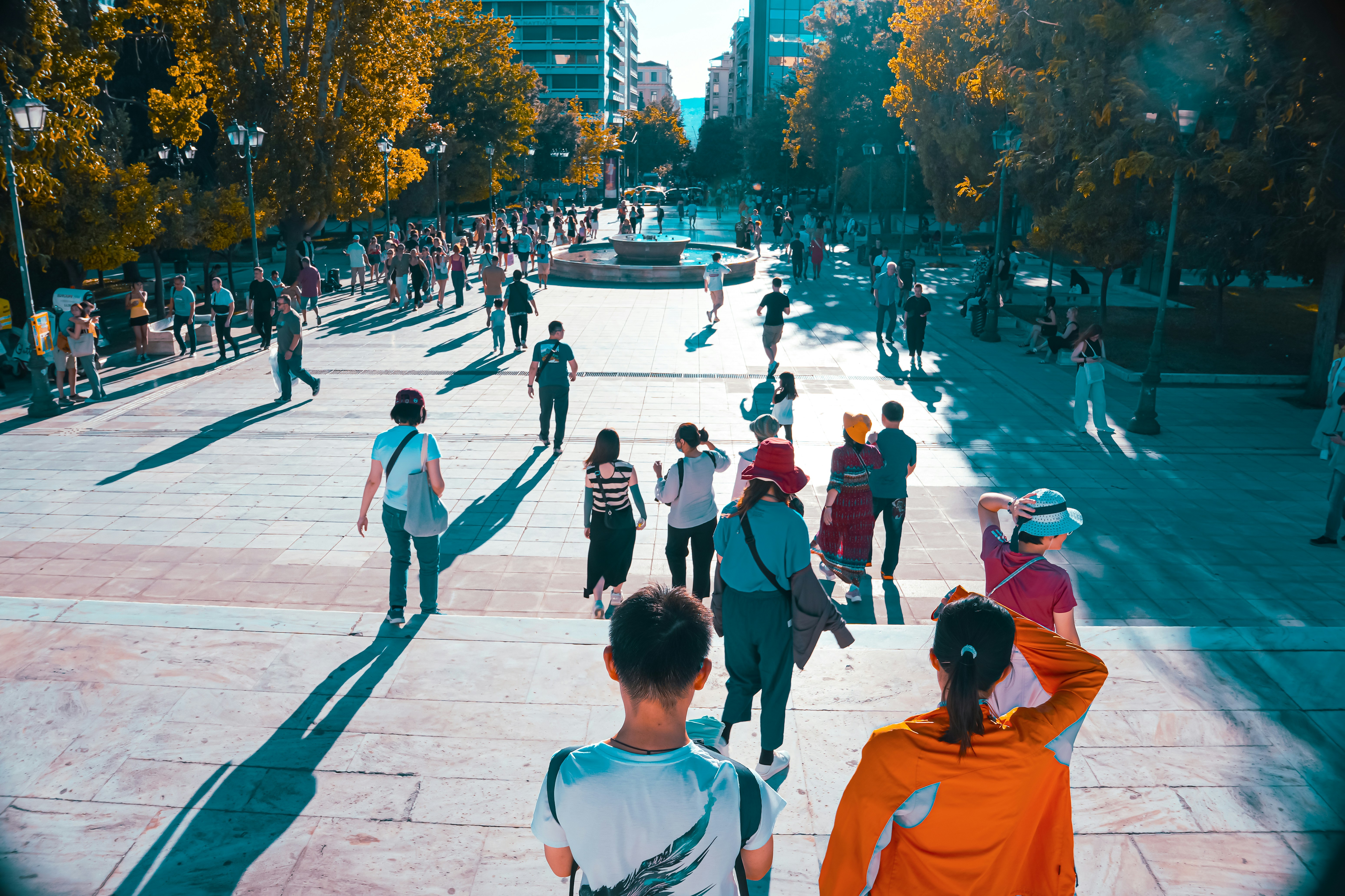 A group of people walking down a street next to tall buildings