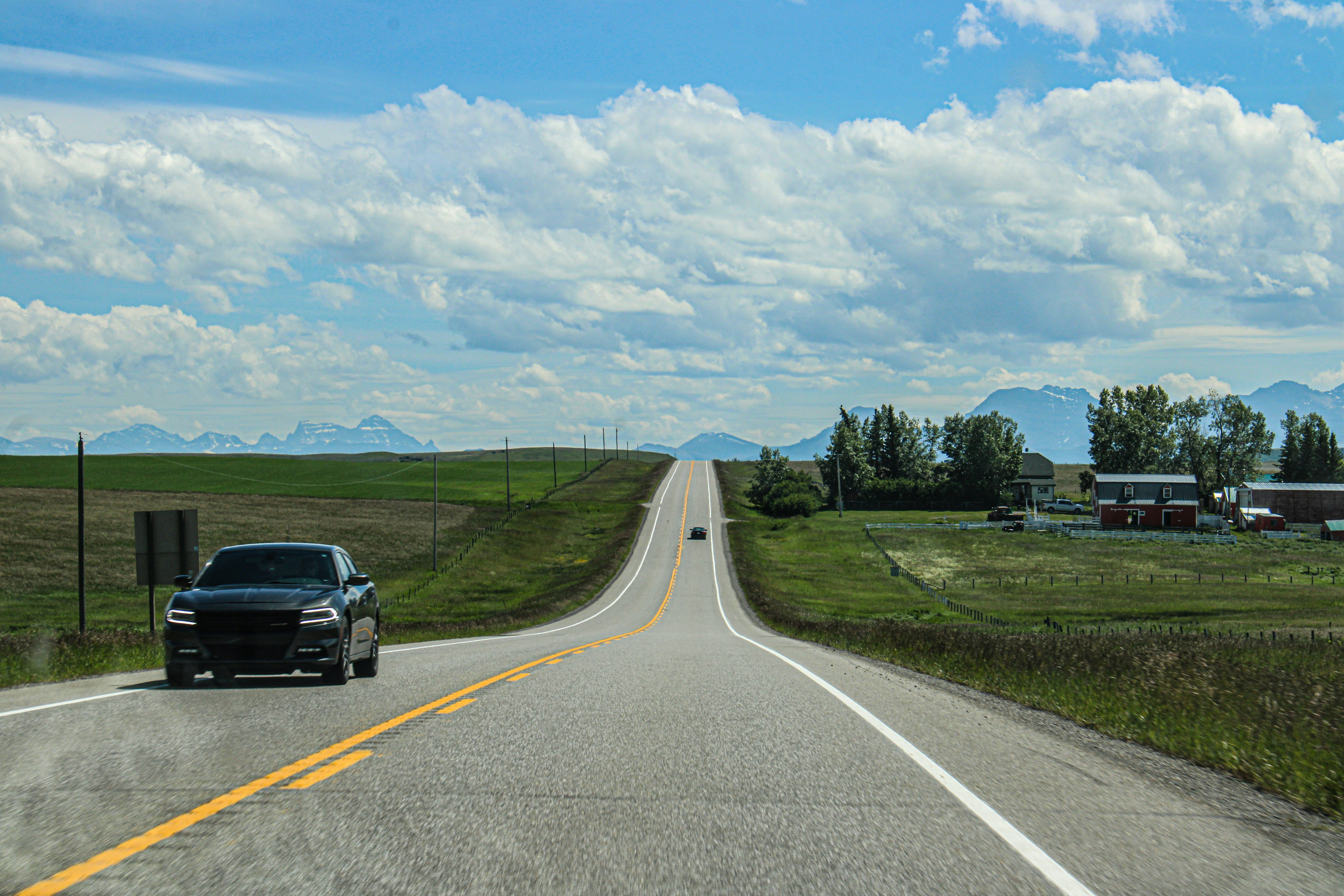 A black car driving down a rural road
