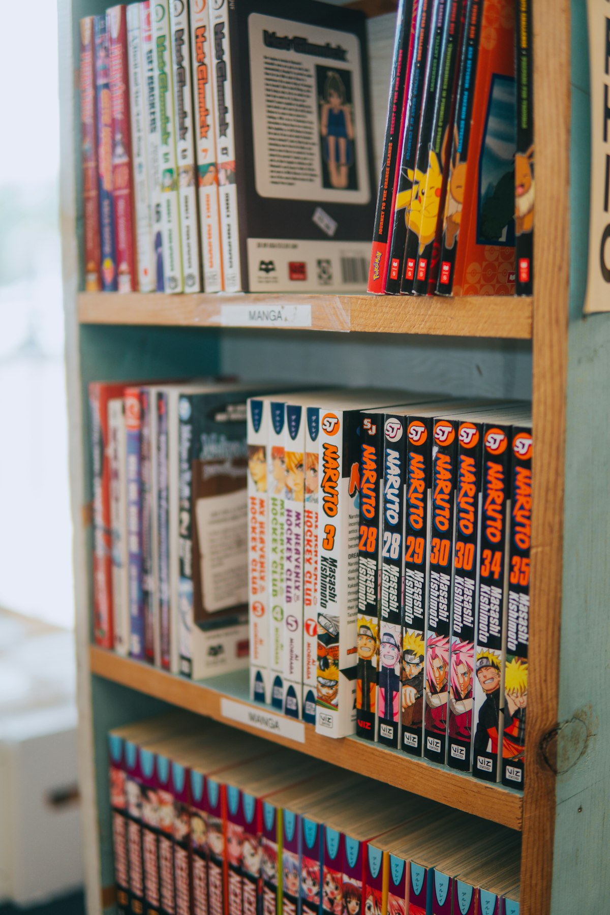 Koleksi manga Naruto berderet rapi di rak buku perpustakaan lengkap dengan label kategori menjadi sumber adaptasi anime populer