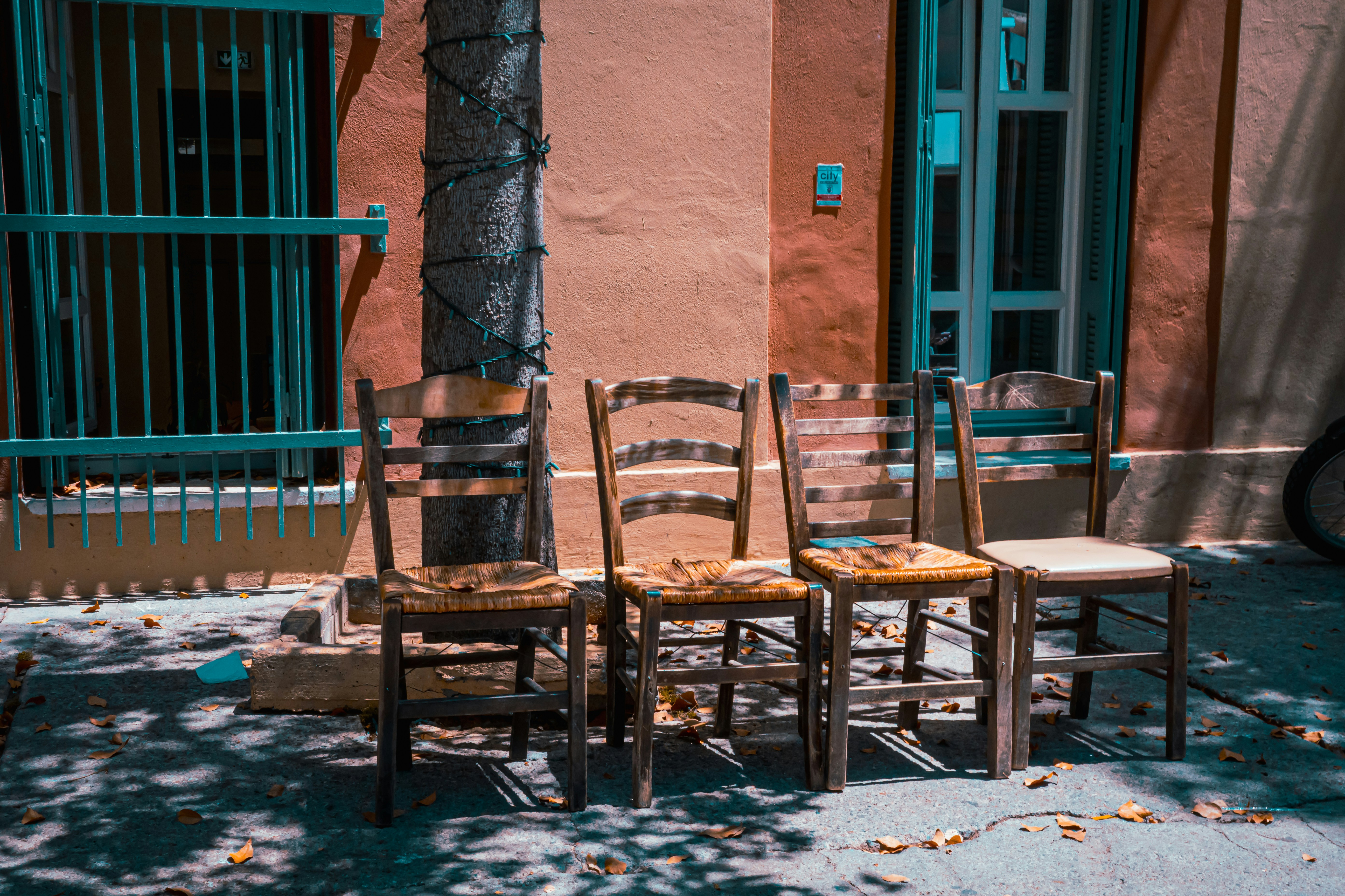 A group of wooden chairs sitting on top of a sidewalk