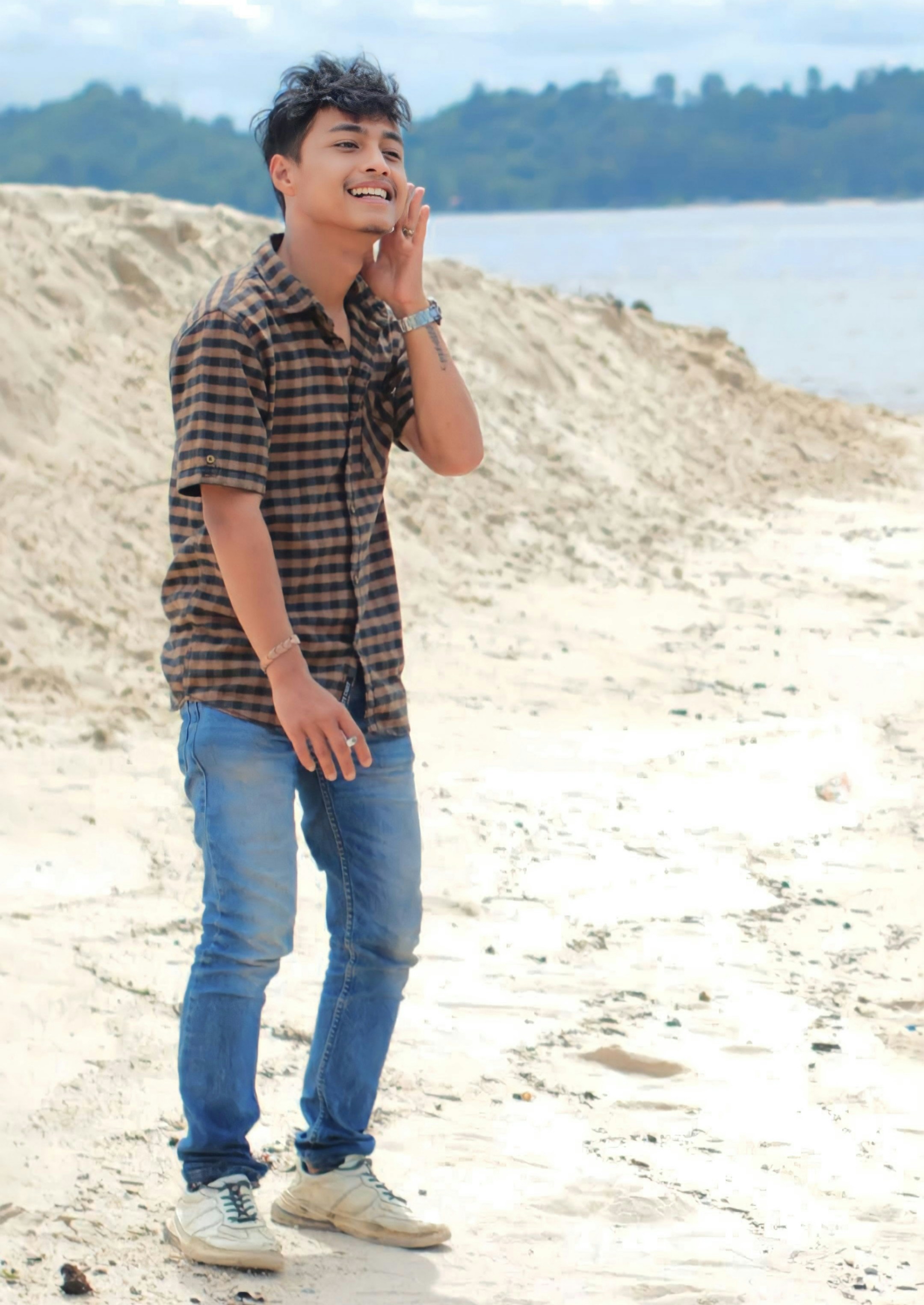 Seorang pria berdiri di pantai berbicara di ponsel
