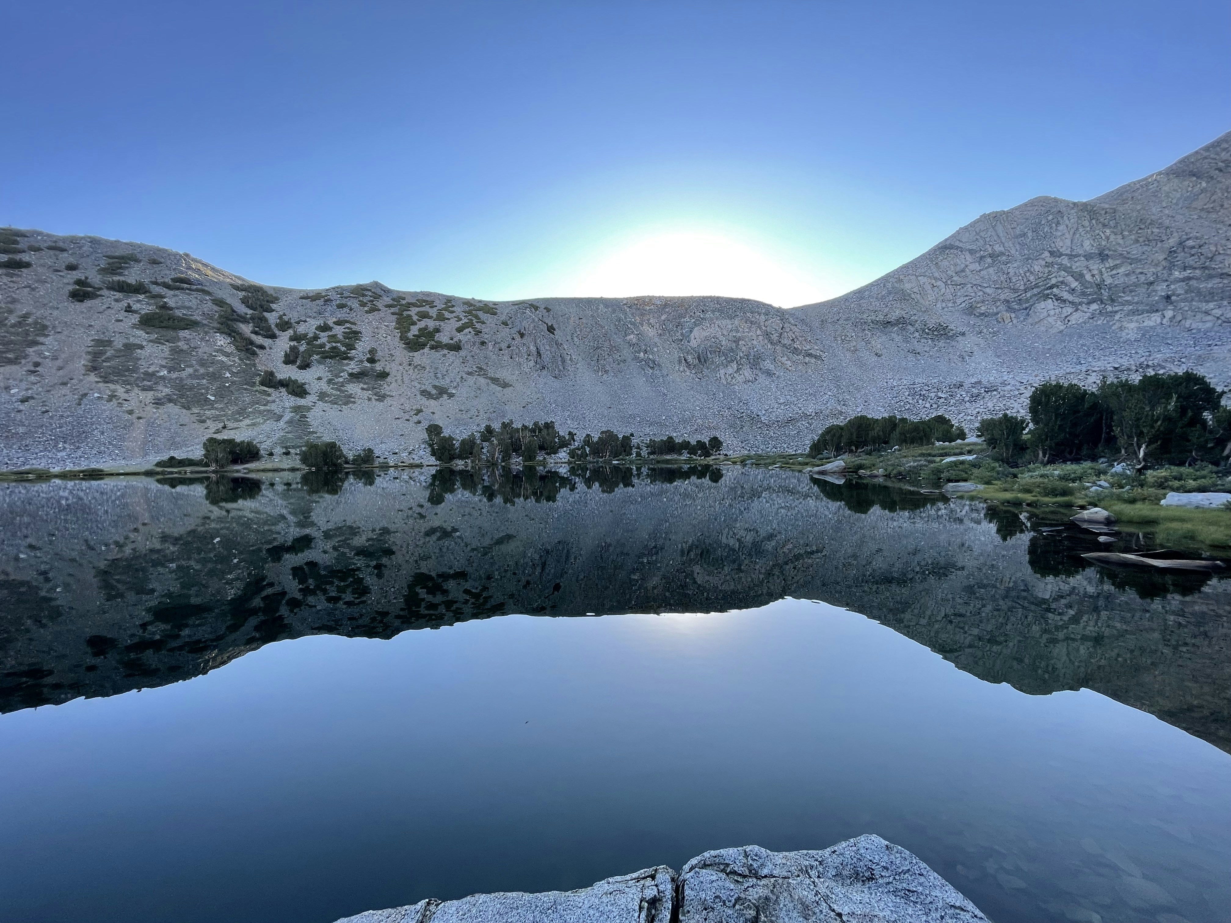 The sun is setting over a mountain lake