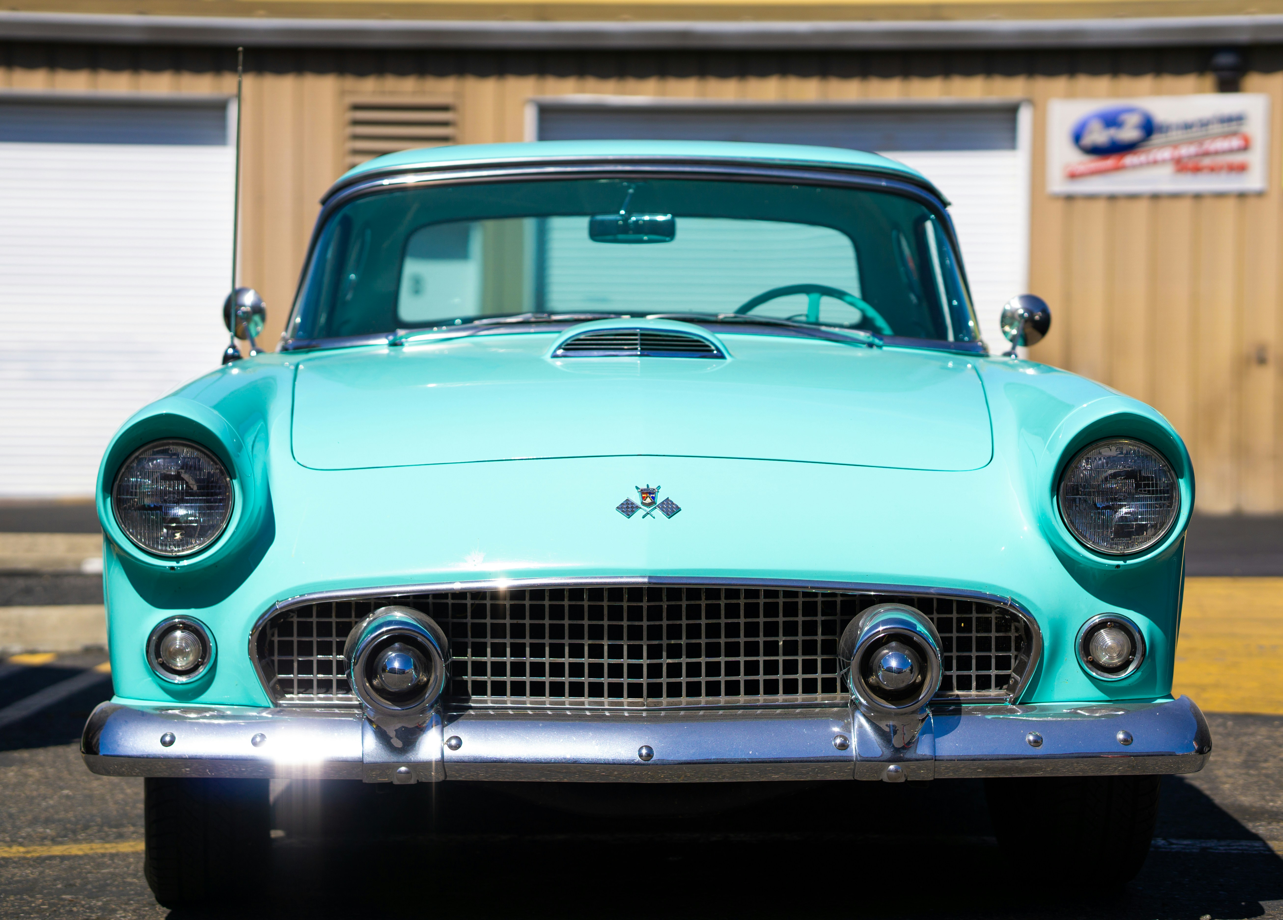 A turquoise classic car parked in a parking lot