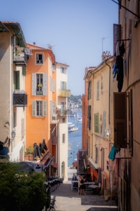 A narrow street with buildings and boats in the water
