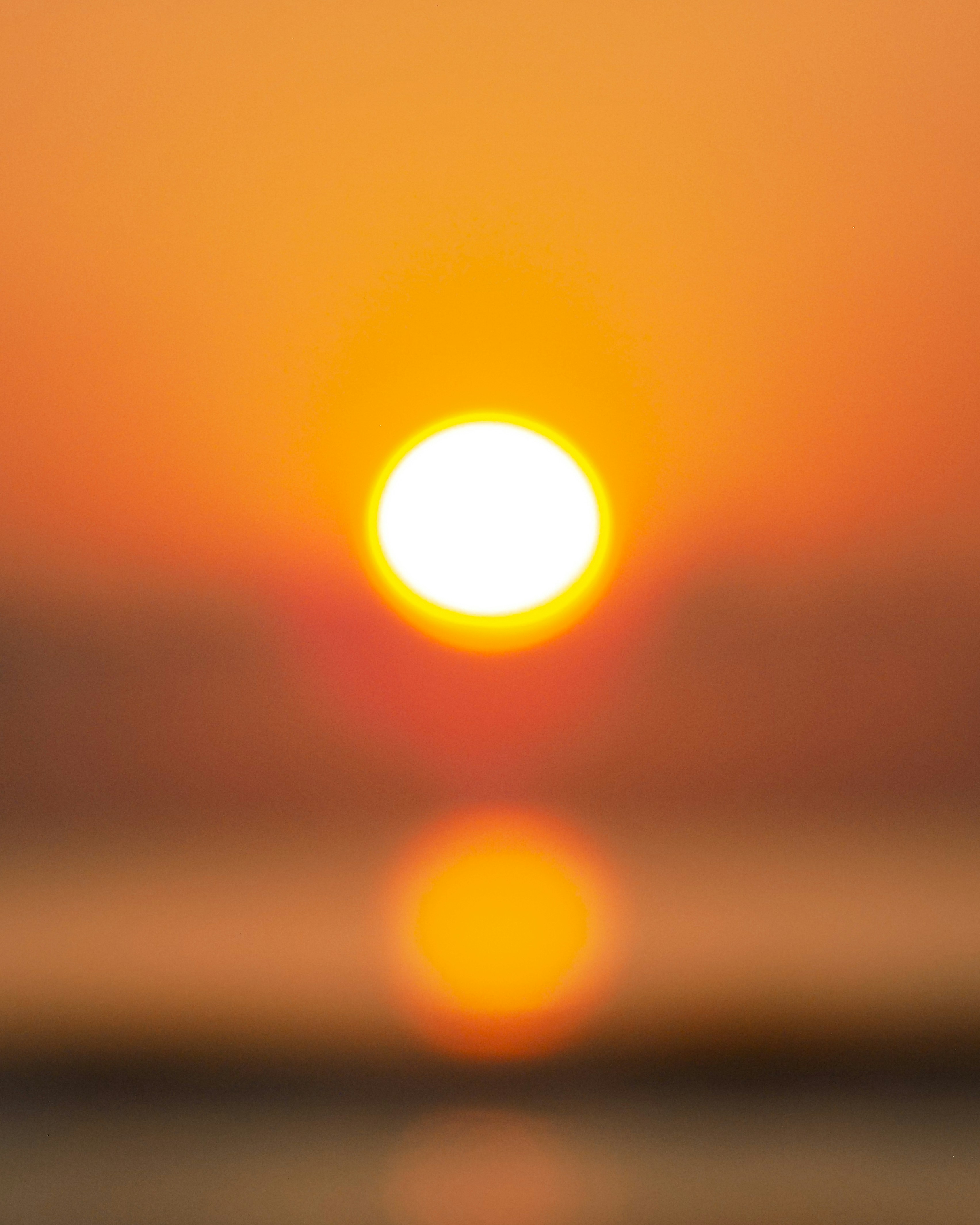 A blurry photo of the sun setting over the ocean