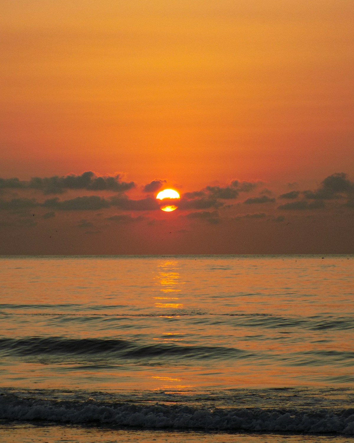 The sun setting over the sea on a cloudy day