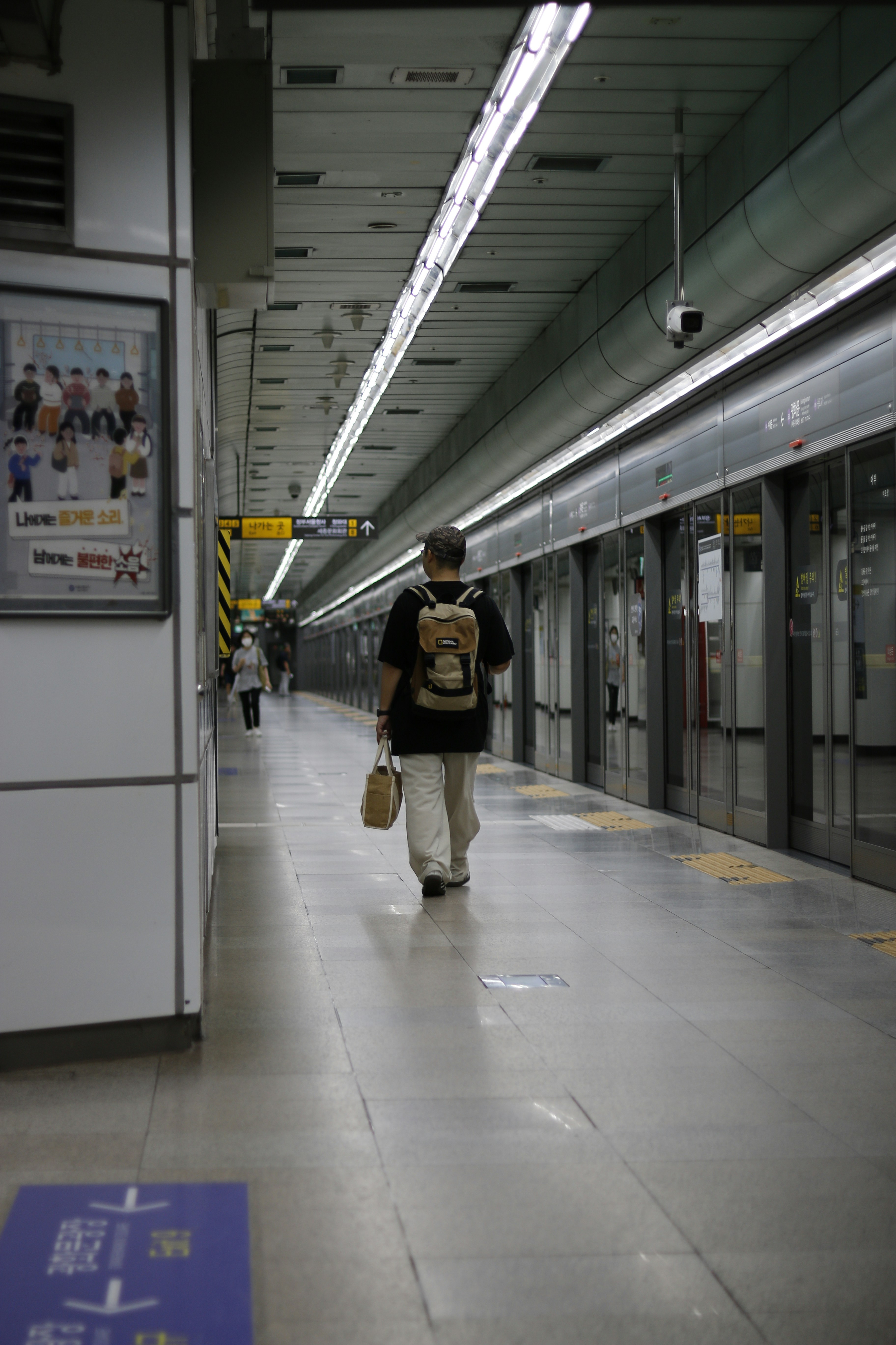 A man walking down a subway platform next to a train