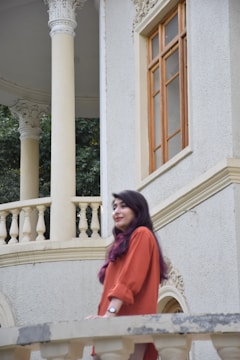 A woman standing on a balcony next to a building