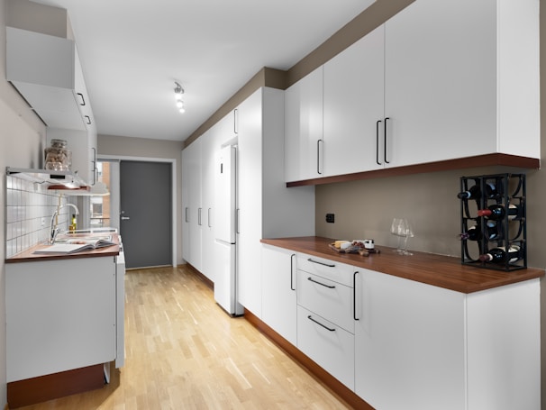 A kitchen with white cabinets and a wooden floor