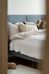 A bed with white sheets and pillows in a room