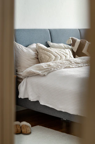 A bed with white sheets and pillows in a room
