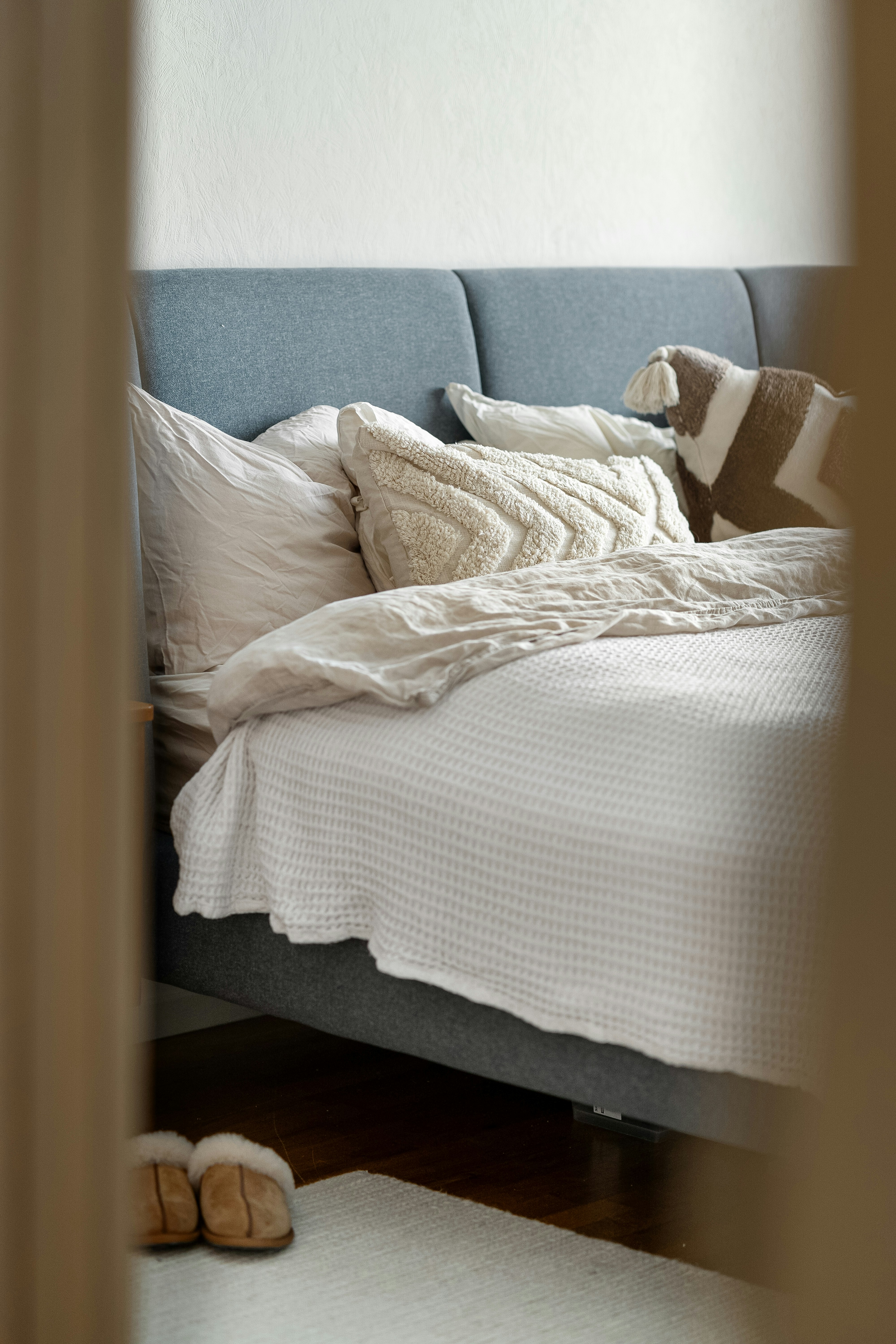 A bed with white sheets and pillows in a room